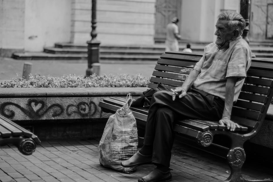 photo of older man sitting on bench smoking to illustrate a story on peripheral arterial disease